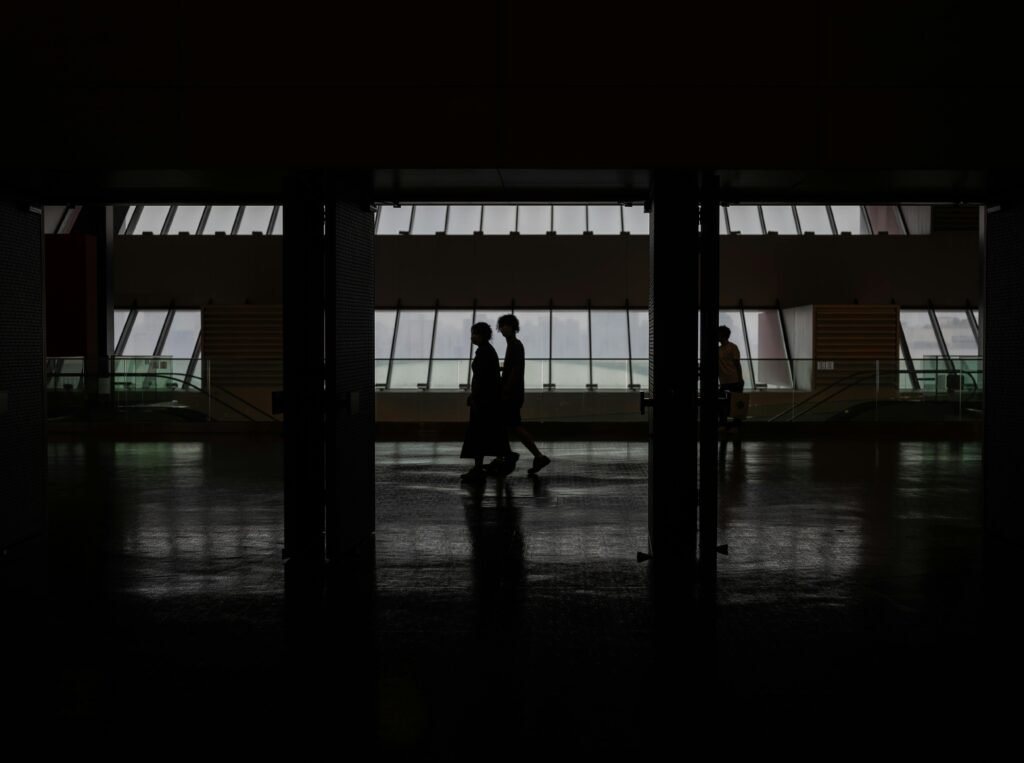 Home Silhouette of people walking through a modern hallway with large windows in Shanghai, China.